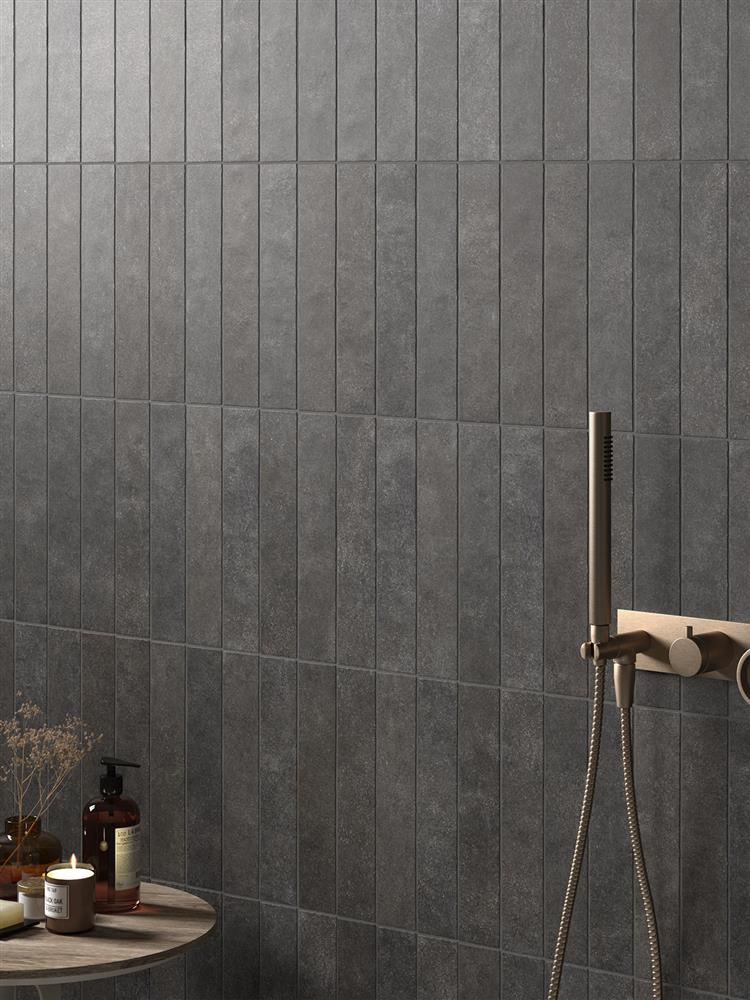 Dark charcoal grey metro tiles in a shower with gold brassware